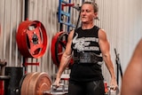 Athelia Soley's veins bulge in her forehead and arms as she lifts a weight in a gym.