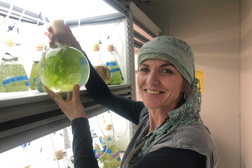 Woman holding seaweed in a glass bottle