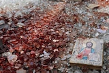 A blood-stained icon of Jesus lies among blood-soaked shattered glass in the back of a truck.