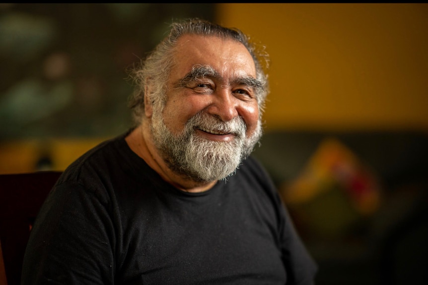 A man with a graying beard in a black t-shirt.