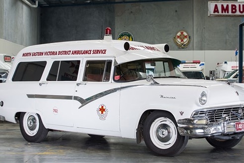 An old paddy wagon car with the ambulance logo, a siren and North Eastern Victoria District Ambulance Service on the side