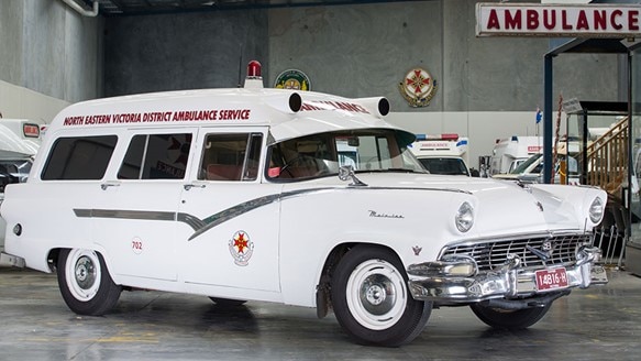 An old paddy wagon car with the ambulance logo, a siren and North Eastern Victoria District Ambulance Service on the side.