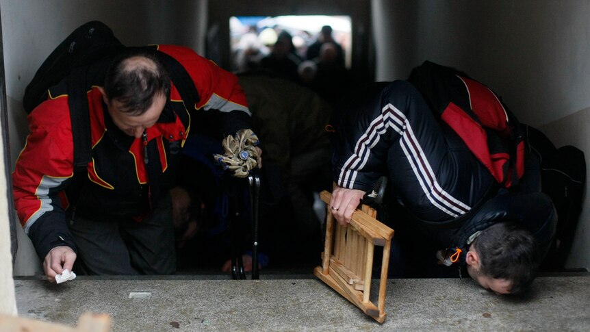 Polish devotees kiss stairs as they kneel during the procession of the Way of the Cross on Good Friday