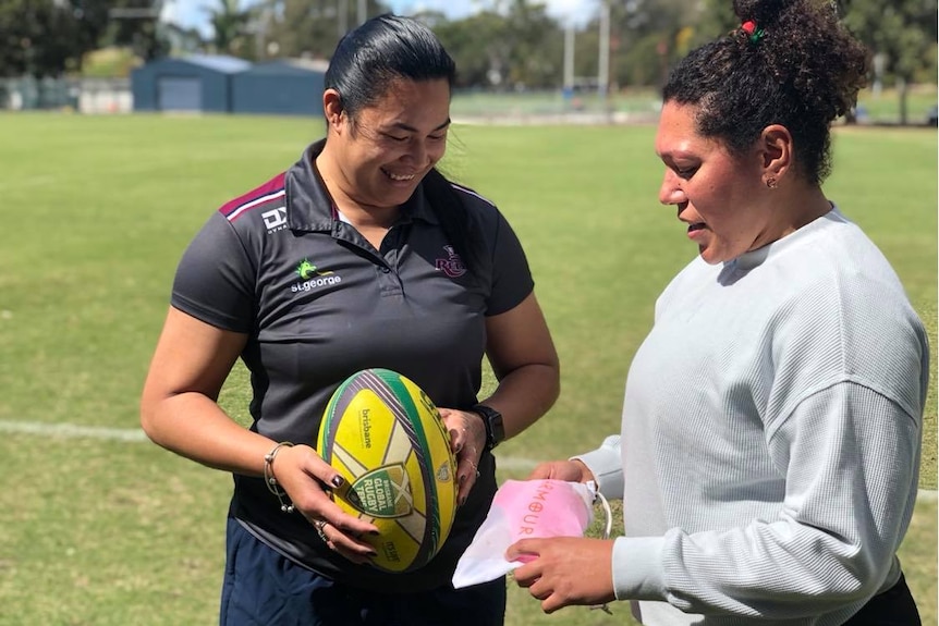 Alisi Qalo-Wilson (left) and Liz Patu (right). Liz is showing Alisi a package containing a sports bra.