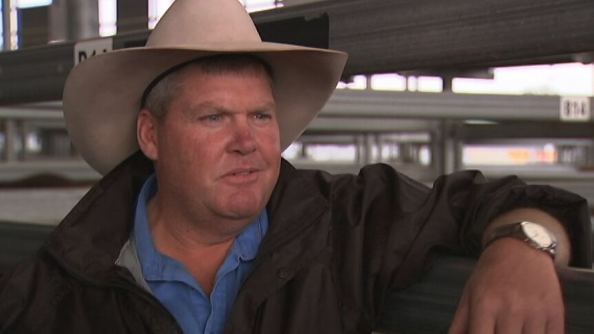 Patrick Purtle, wearing an Akubra hat, leans up against a gate