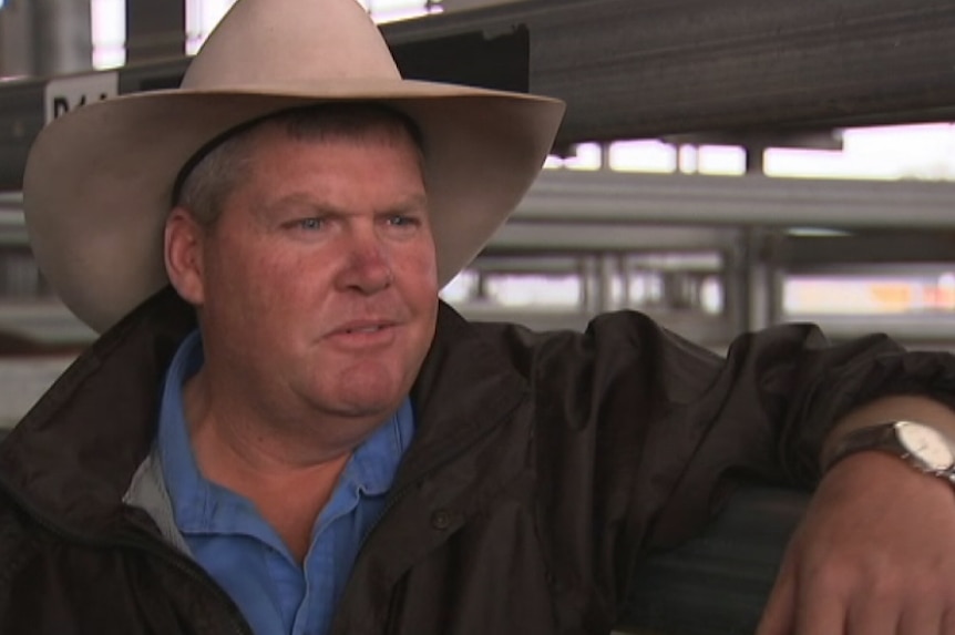 Patrick Purtle, wearing an Akubra hat, leans up against a gate