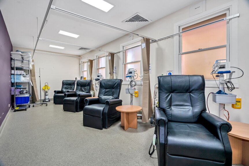 Several arm chairs in an empty room surrounded by medical equipment.