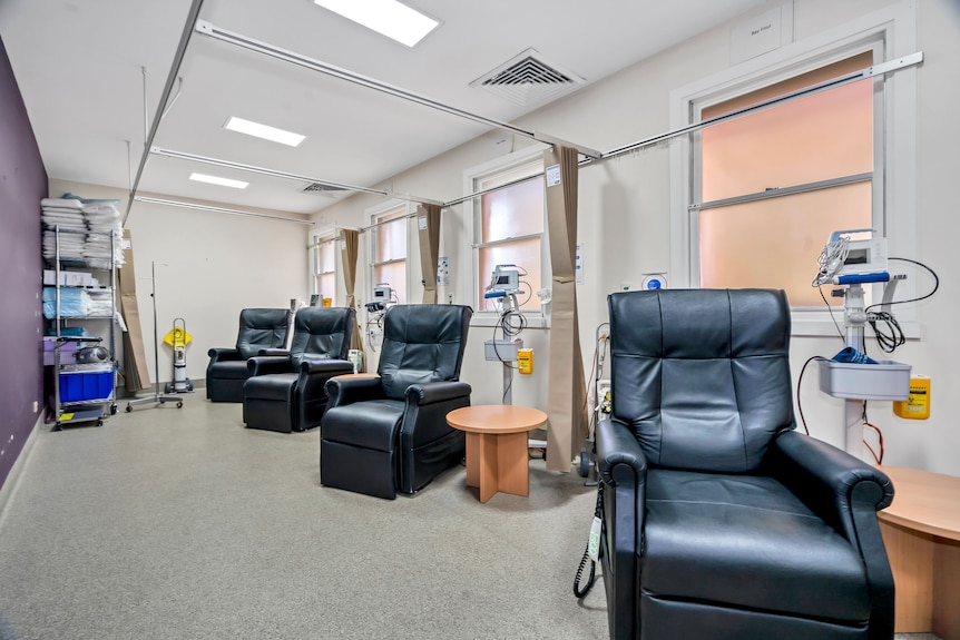 Several arm chairs in an empty room surrounded by medical equipment.