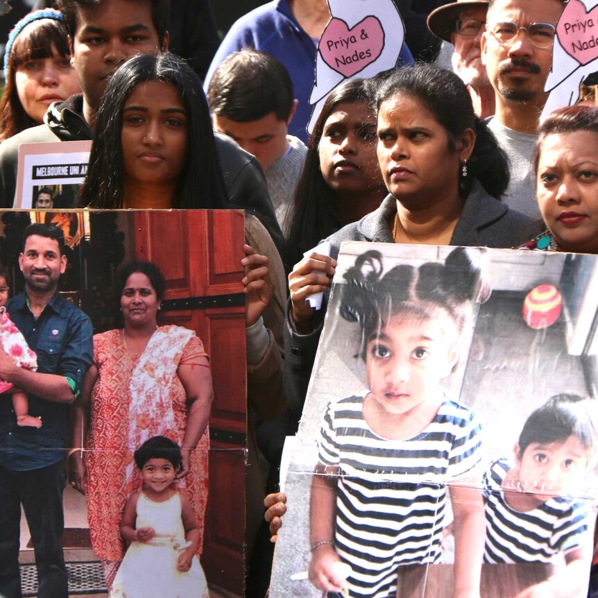 People hold photos of the Tamil family from Biloela at a rally.