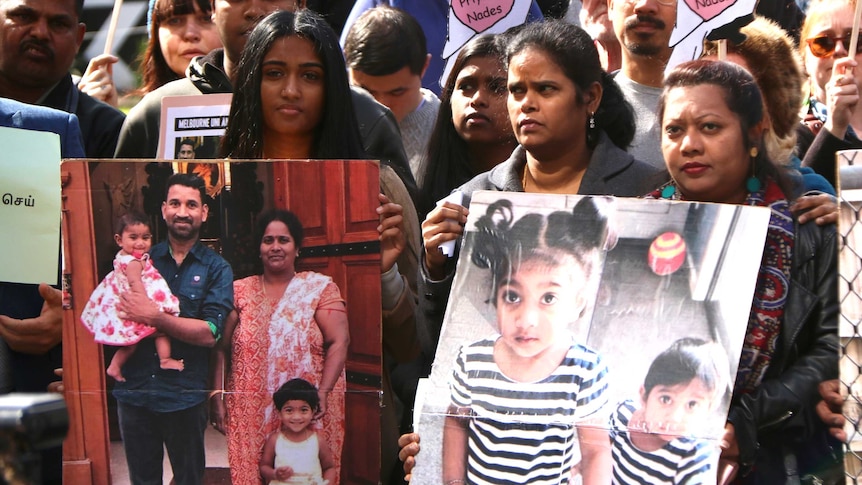 People hold photos of the Tamil family from Biloela at a rally.