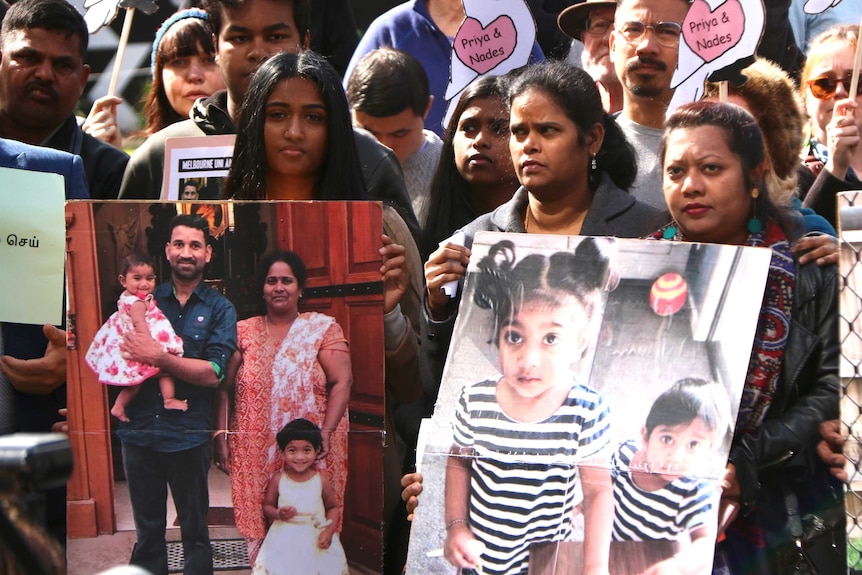 People hold photos of the Tamil family from Biloela at a rally.