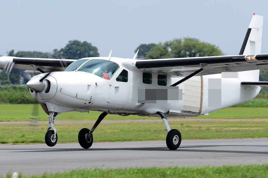 A Cessna 208B Grand Caravan aircraft takes off from an airport.