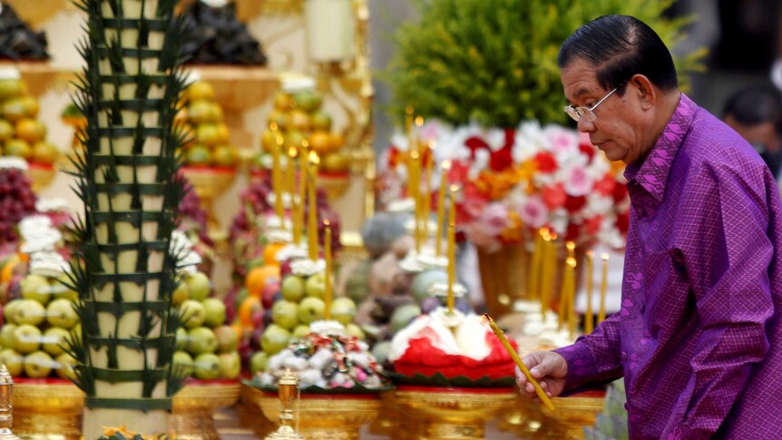 Wearing Purple, Hun sen lights a symbolic candle in the gold decorated interior of the Angkor Wat temple