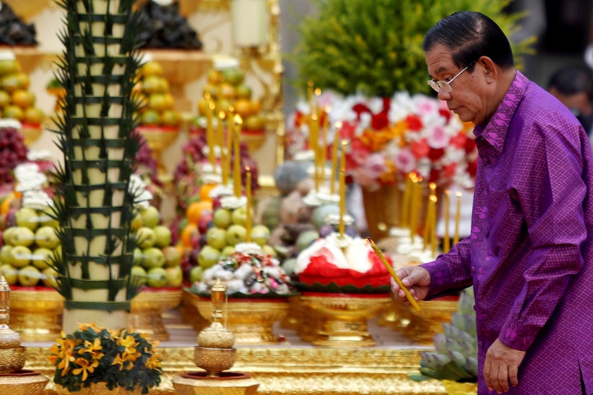 Wearing Purple, Hun sen lights a symbolic candle in the gold decorated interior of the Angkor Wat temple