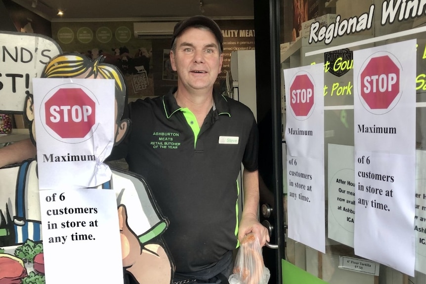 Ashburton Meats manager Steve Goodman stands beside his signs outlining social-distancing measures in the store.