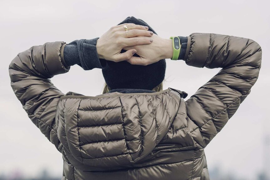 A woman wearing a puffer jacket puts her hands on her head