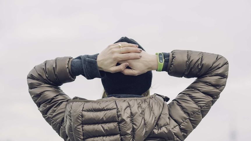 A woman wearing a puffer jacket puts her hands on her head