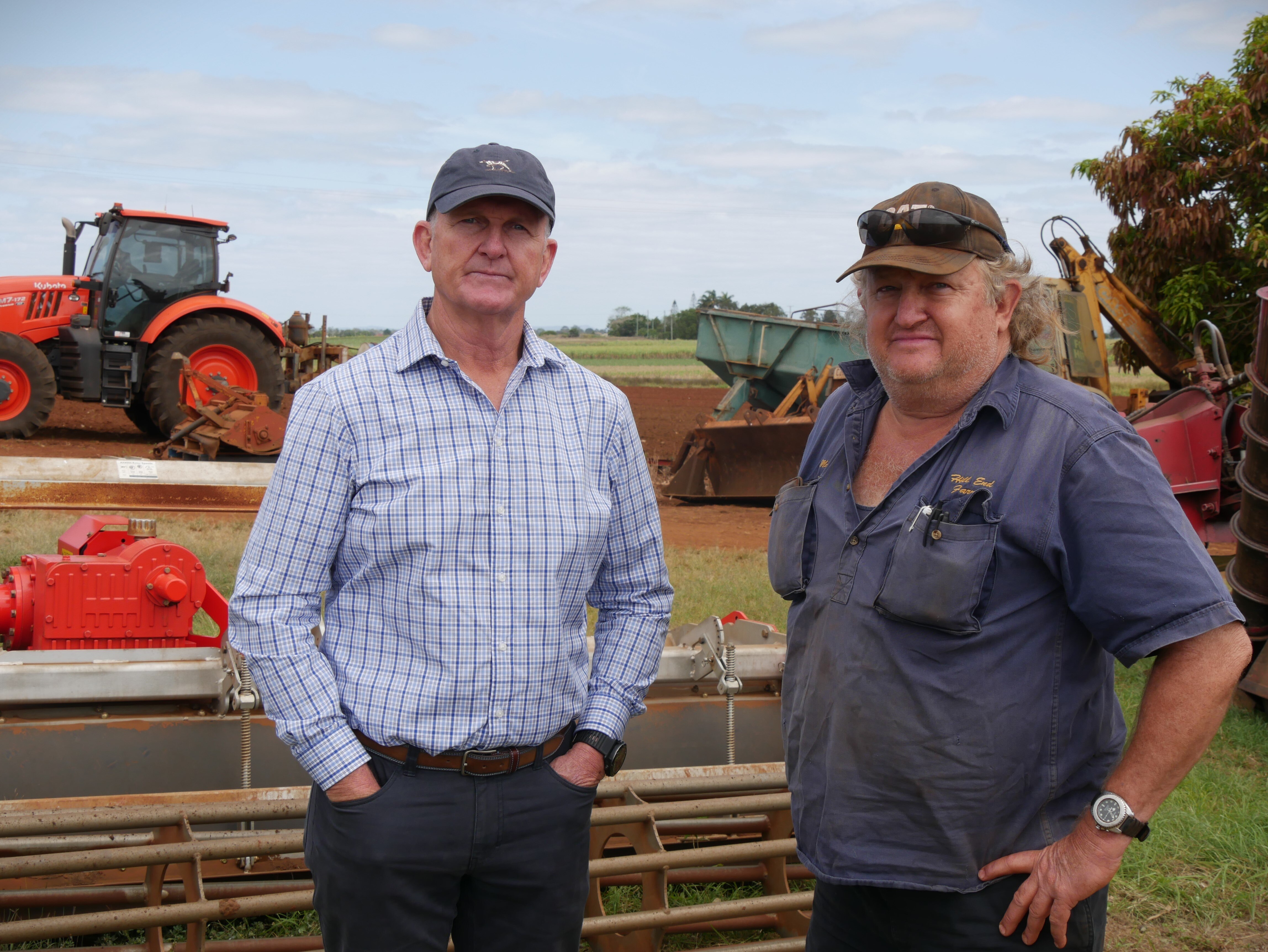 Two men standing around farming machinery