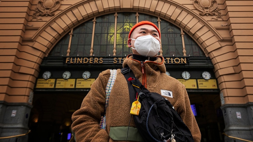 Will poses for a photo wearing a mask in front of Flinders Street Station in Melbourne, Friday, July 17, 2020.