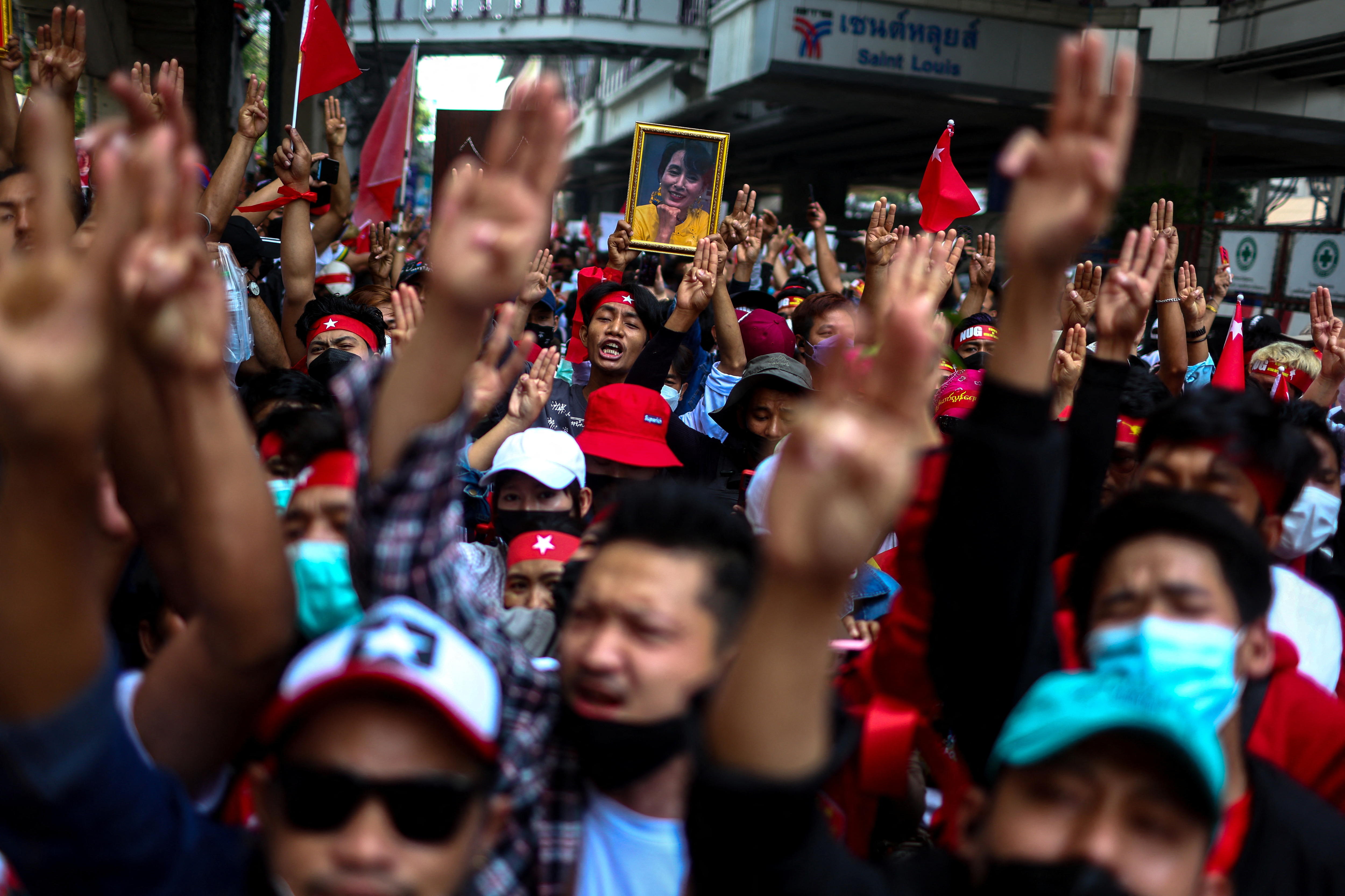 A crowd of protesters wearing red salute with three fingers.