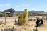 A yellow tank with "don't dump on SA" written on it at a road intersection.