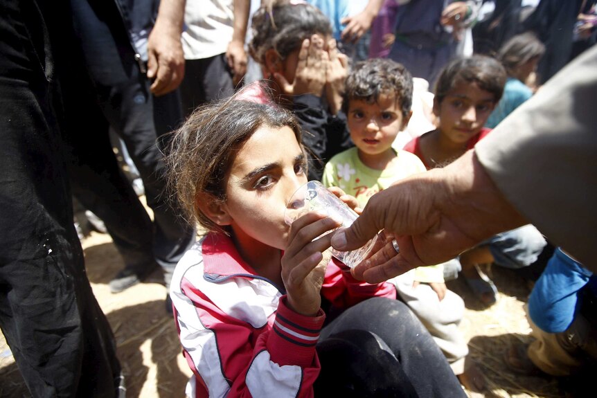 A Syrian refugee girl drinks water after crossing into Turkey from the Syria