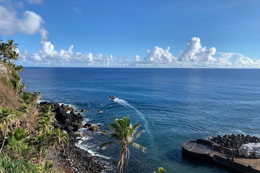 Una giornata di sole con acque blu profonde, che mostra una barca che esce dalle Isole Pitcairn. 