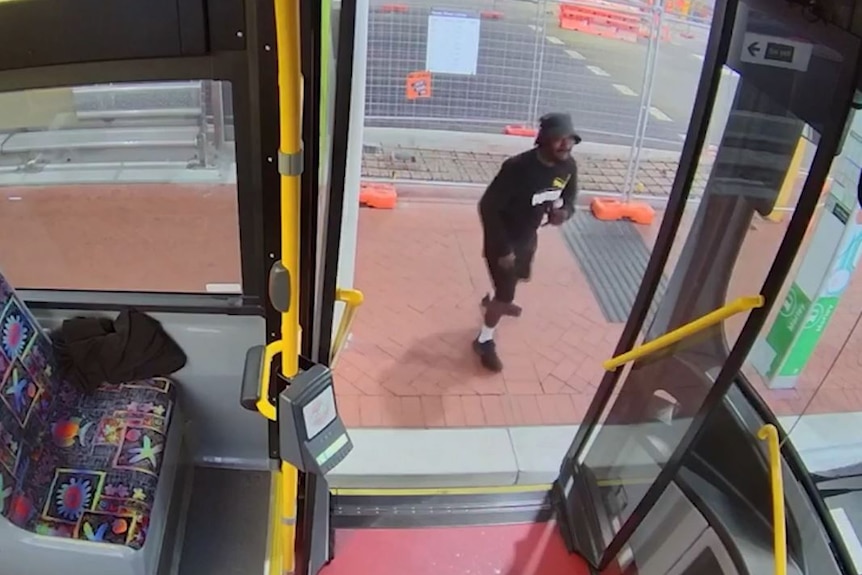 A man stands outside a bus. 