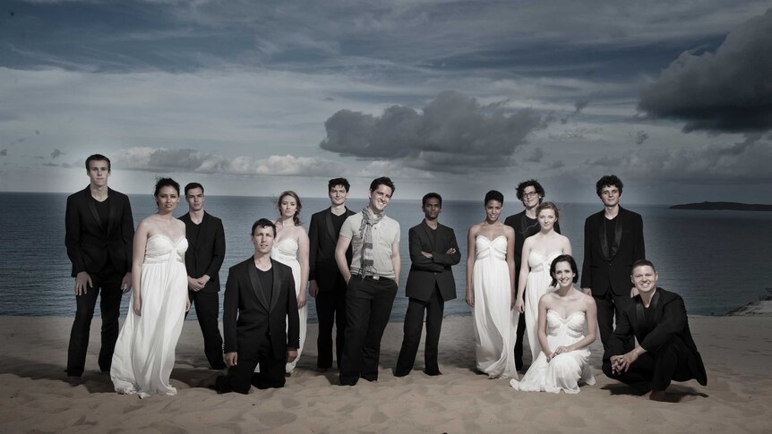 The members of The Australian Voices standing in formal attire on a beach.