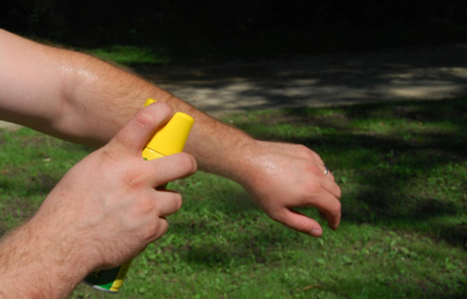 A man sprays his arm with repellent.