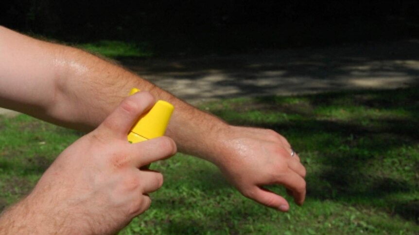 A man sprays his arm with repellent.
