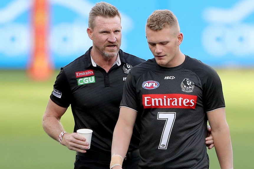 The Collingwood AFL coach walks alongside one of the Magpies players before a match in Perth.