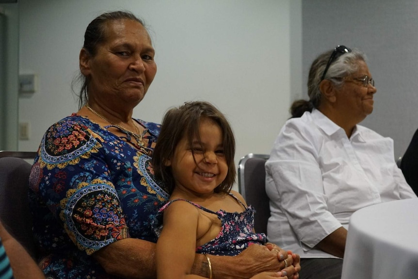 A woman and child look at the camera while sitting at a table.