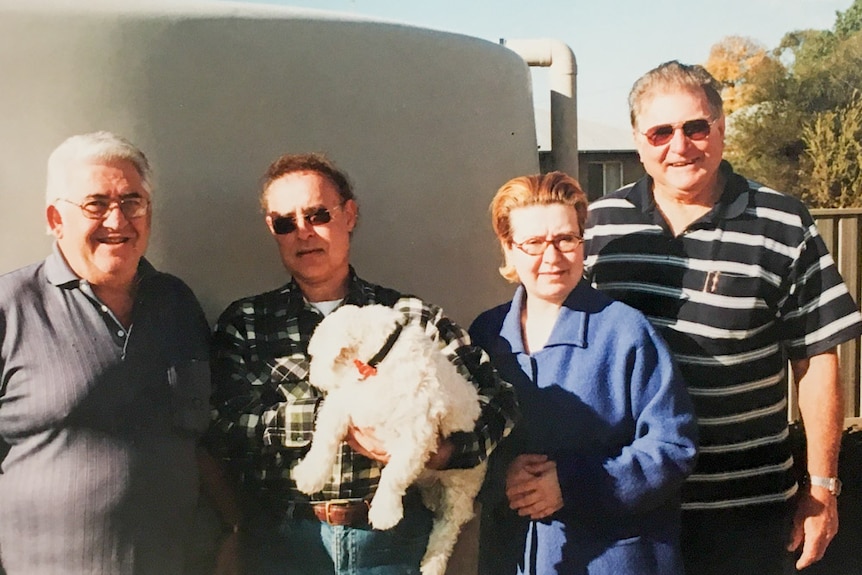 Four men and a woman stand in front of a water tank