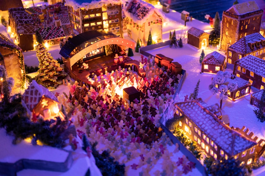 A gingerbread model concert shows a crowd made from sweets watching a band on a gingerbread stage.