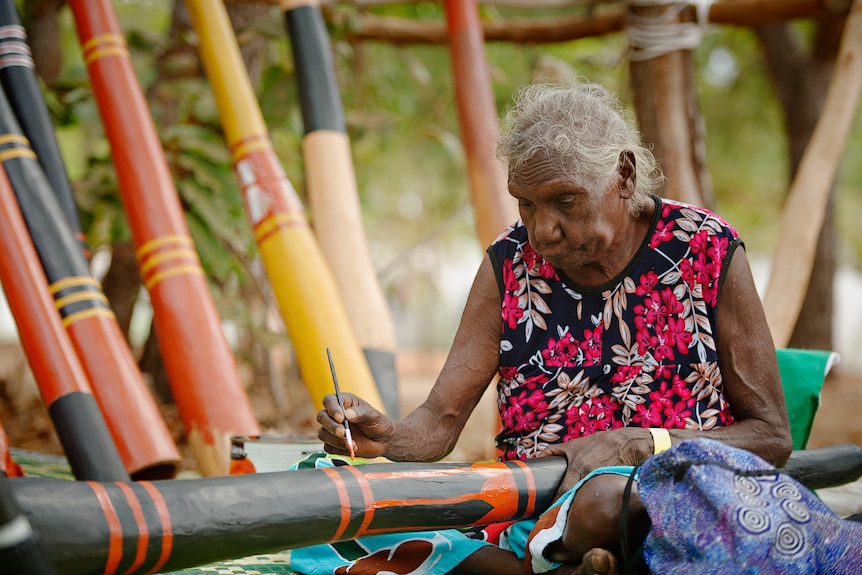 A woman painting a didgeridoo