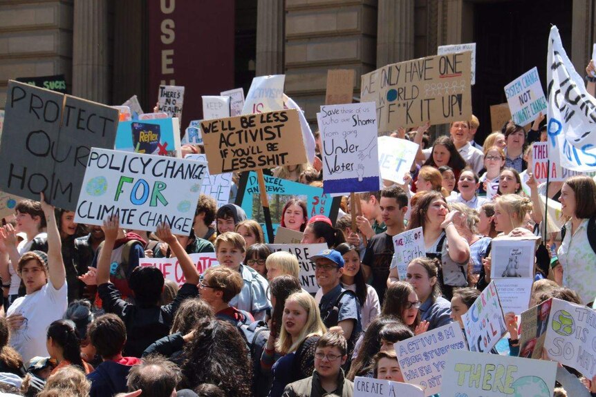 A mob of students are hold placards on the steps on Melbourne's Parliament House.