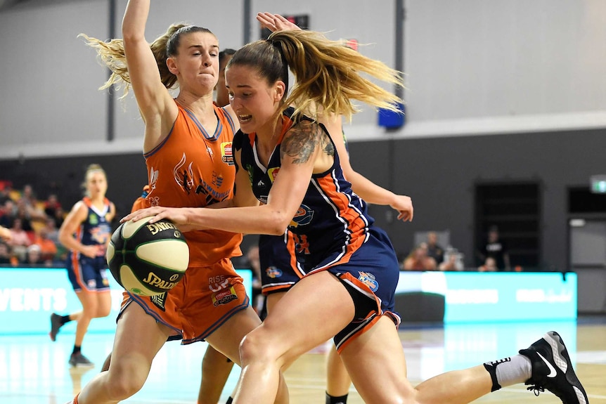 A WNBL player bounces a basketball while being defended against by an opponent.