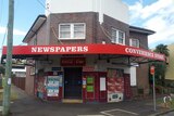 Exterior of an old corner shop advertising newspapers. 