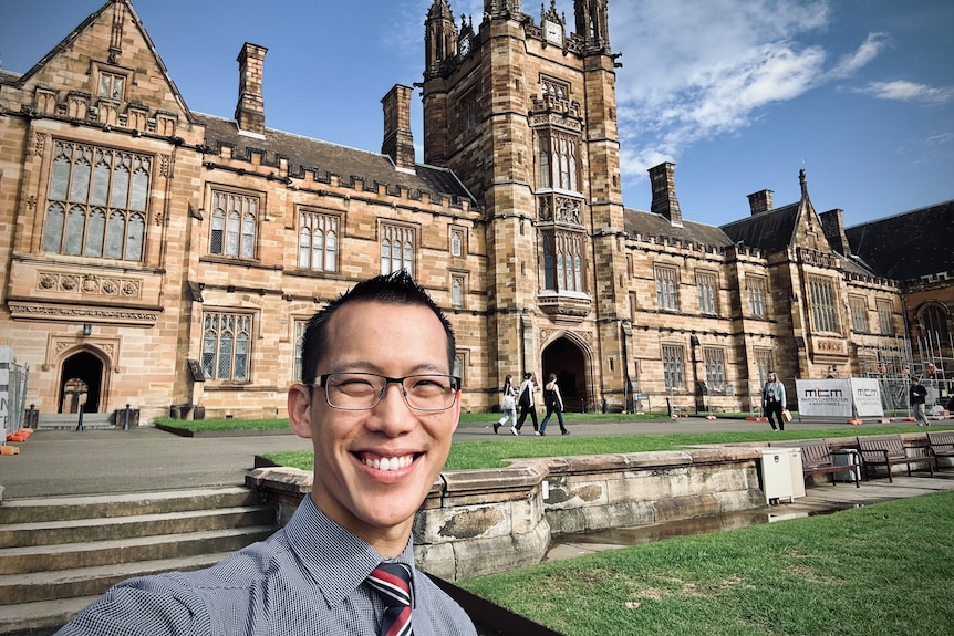 maths teacher Eddie Woo takes a selfie in front of the University of Sydney's Great Hall where he's a Professor of Practice.