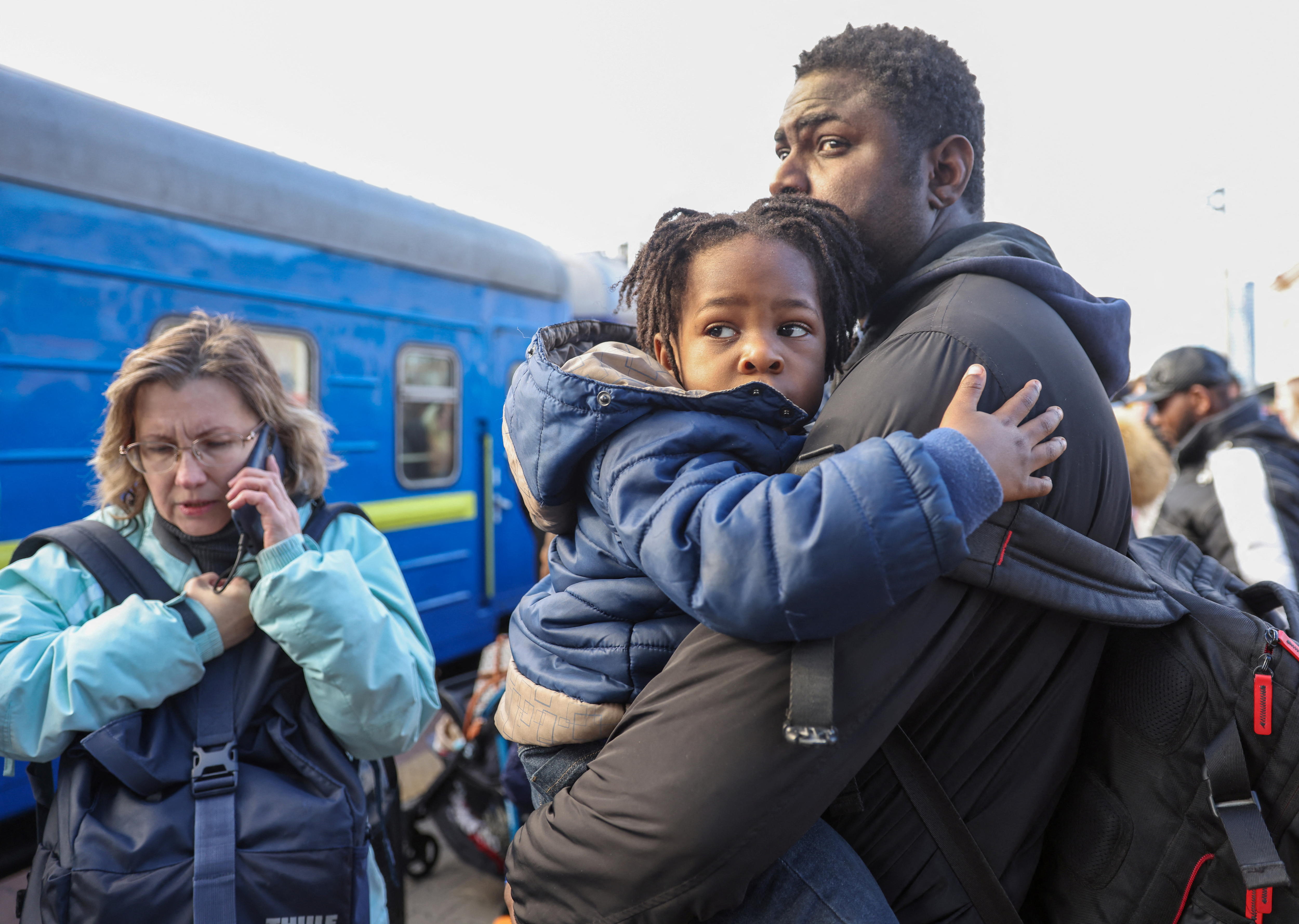 A father holds his young child outside a train.