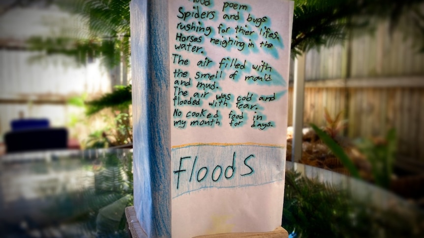 A paper rectangle on a table with 'floods' and writing and blue colouring.