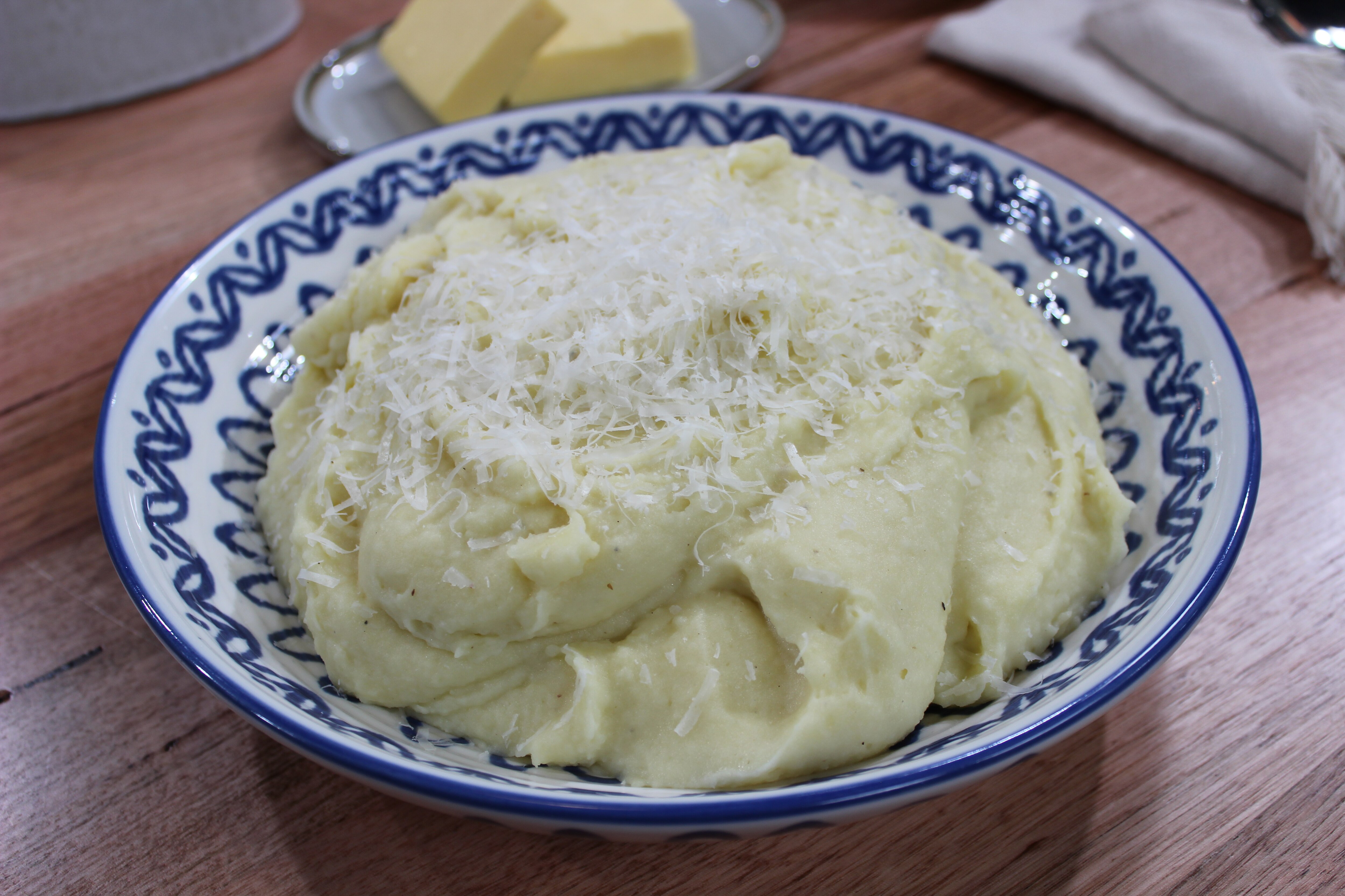 A picture of mashed potatoes with cheese on top in serving bowl.