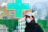 A woman wearing a mask outside a pharmacy