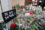 Flowers are laid out on the ground with a sign saying "Je suis Samuel", meaning "I am Samuel"
