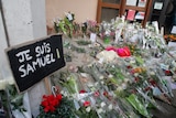 Flowers are laid out on the ground with a sign saying "Je suis Samuel", meaning "I am Samuel"