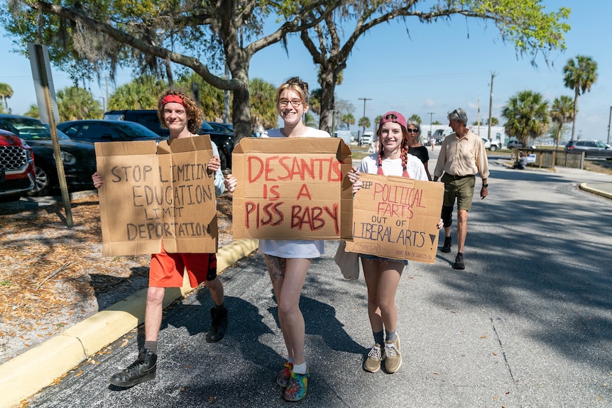 Women walk holding signs.