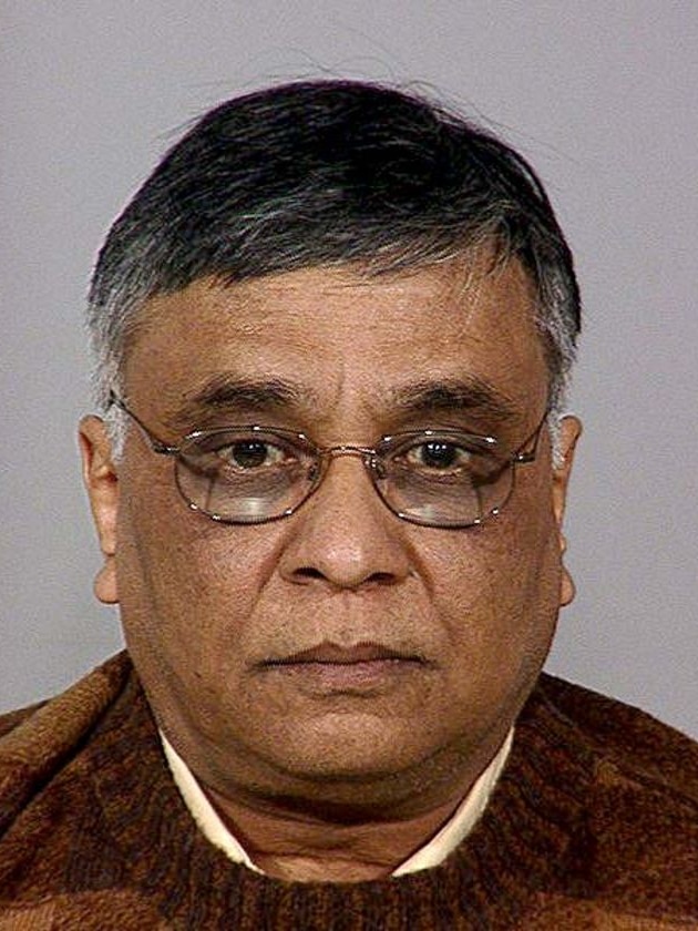 A mugshot of an Indian-American man with glasses and black hair going grey at the temples.