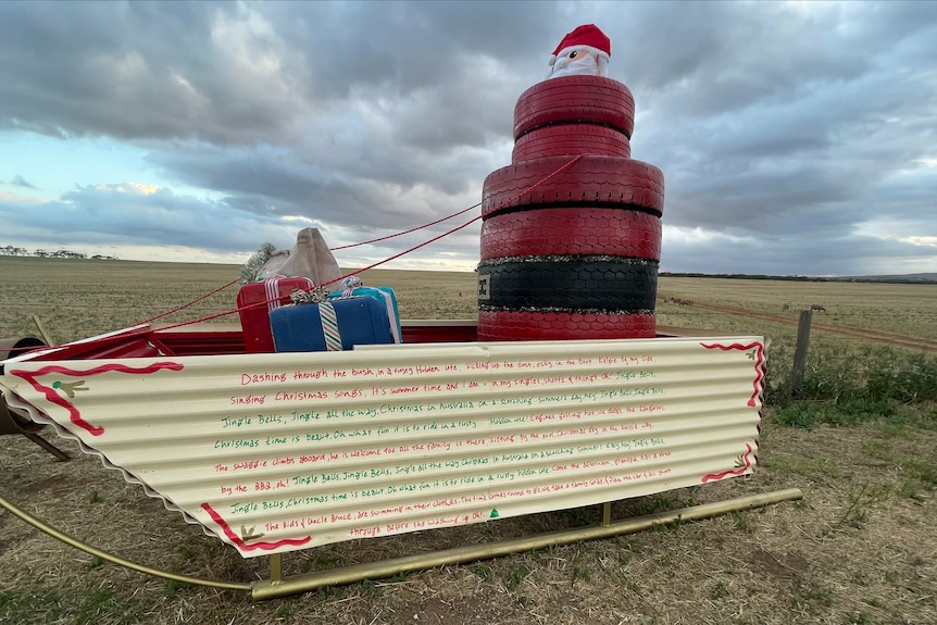 A boat with Santa painted on stacked tyres at a farm entrance