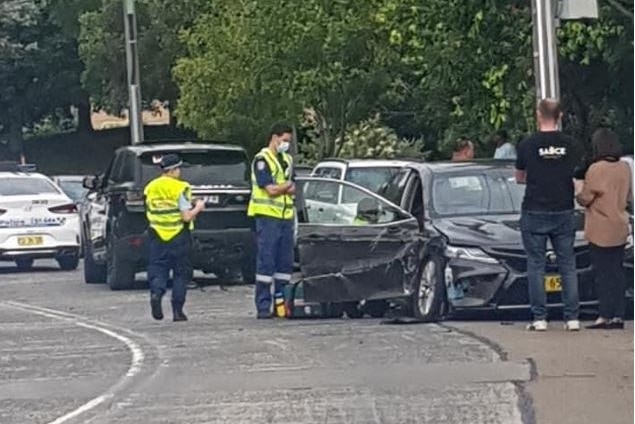 Police surround a black car that has been crushed in a car crash